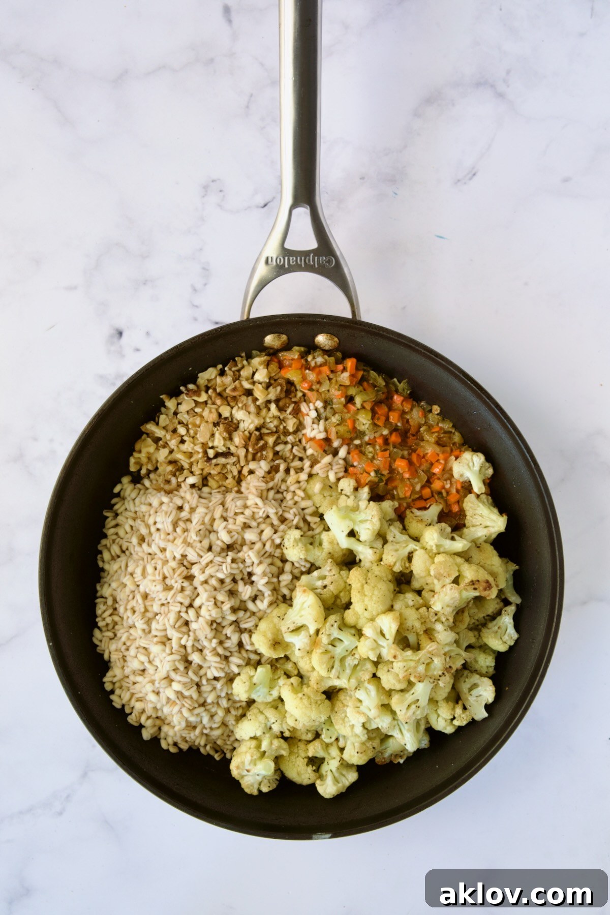 Roasted cauliflower and cooked barley just added to the aromatic mixture in a nonstick skillet, awaiting stirring.