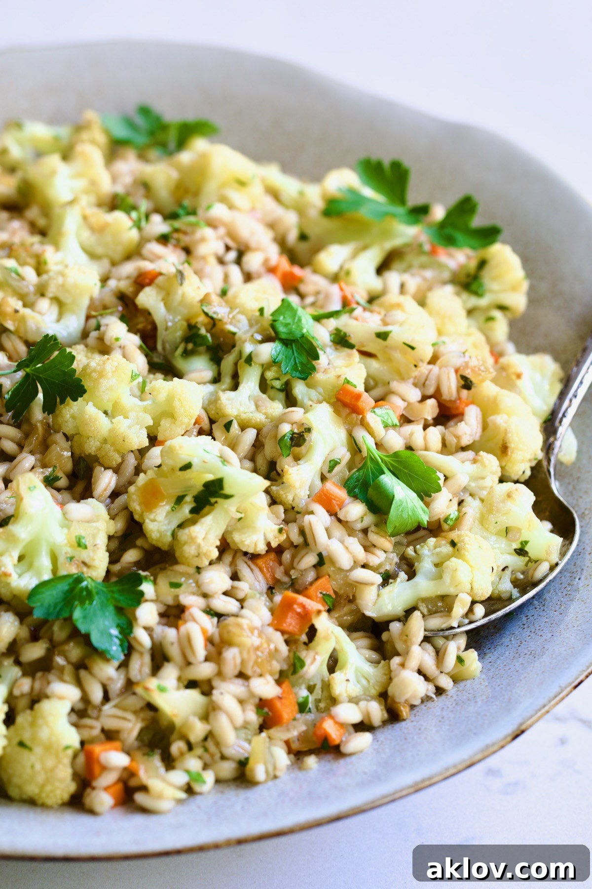 A beautifully presented bowl of Barley Pilaf with Roasted Cauliflower, garnished with vibrant green parsley, ready to be served.