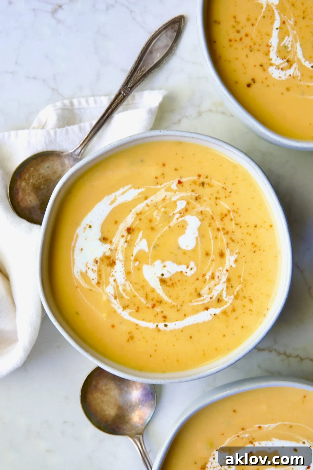 Three generous servings of creamy Butternut Squash Brie Soup presented in elegant white bowls, ready to be enjoyed.