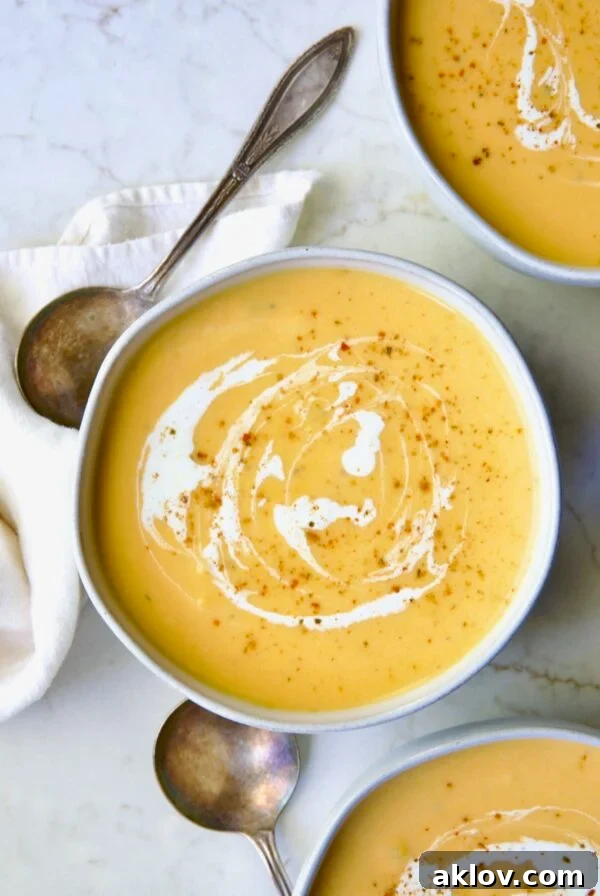 Three servings of Butternut Squash Brie Soup in white bowls.