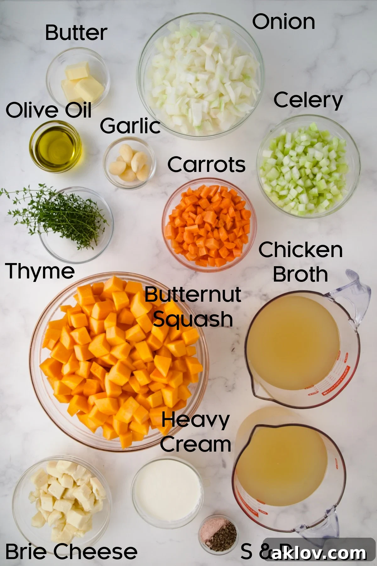 A vibrant selection of fresh ingredients for Butternut Squash Brie Soup arranged in glass bowls, including chopped vegetables, broth, and Brie cheese.