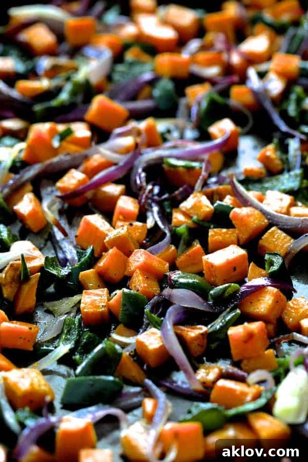 Sheet Pan Magic: Vegetarian Quesadilla Bake 3 Close-up photo of roasted sweet potatoes, poblano peppers, red onion, and black beans on a baking sheet, ready for quesadilla assembly.