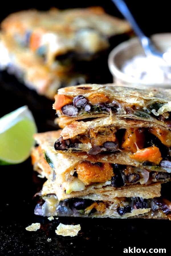 Sheet Pan Magic: Vegetarian Quesadilla Bake 5 Close-up of a stack of four quesadilla wedges, showing the melty cheese and vibrant filling inside, with a dollop of Chipotle Sour Cream in the foreground.