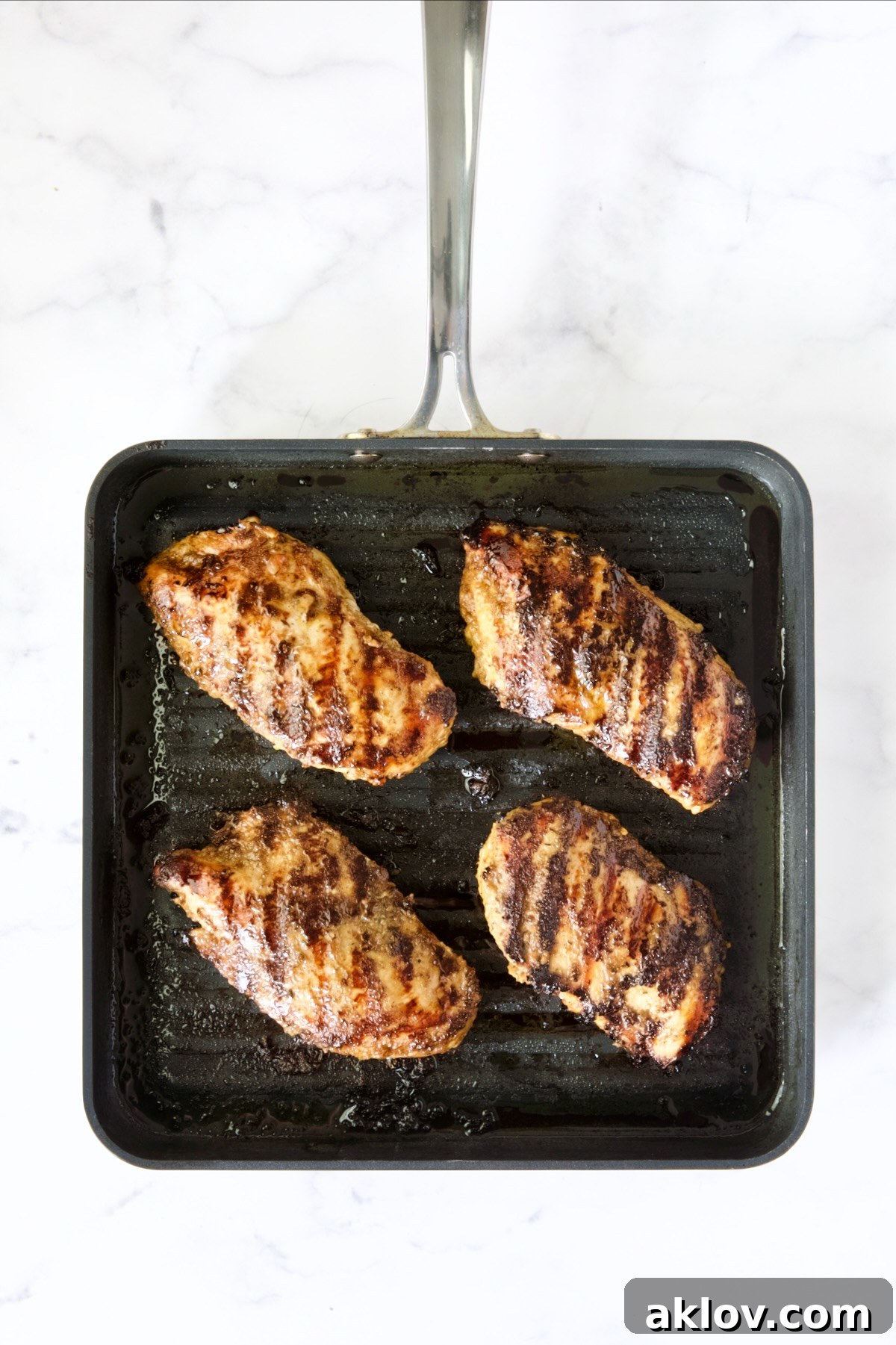 Four grilled chicken breasts on grill pan.