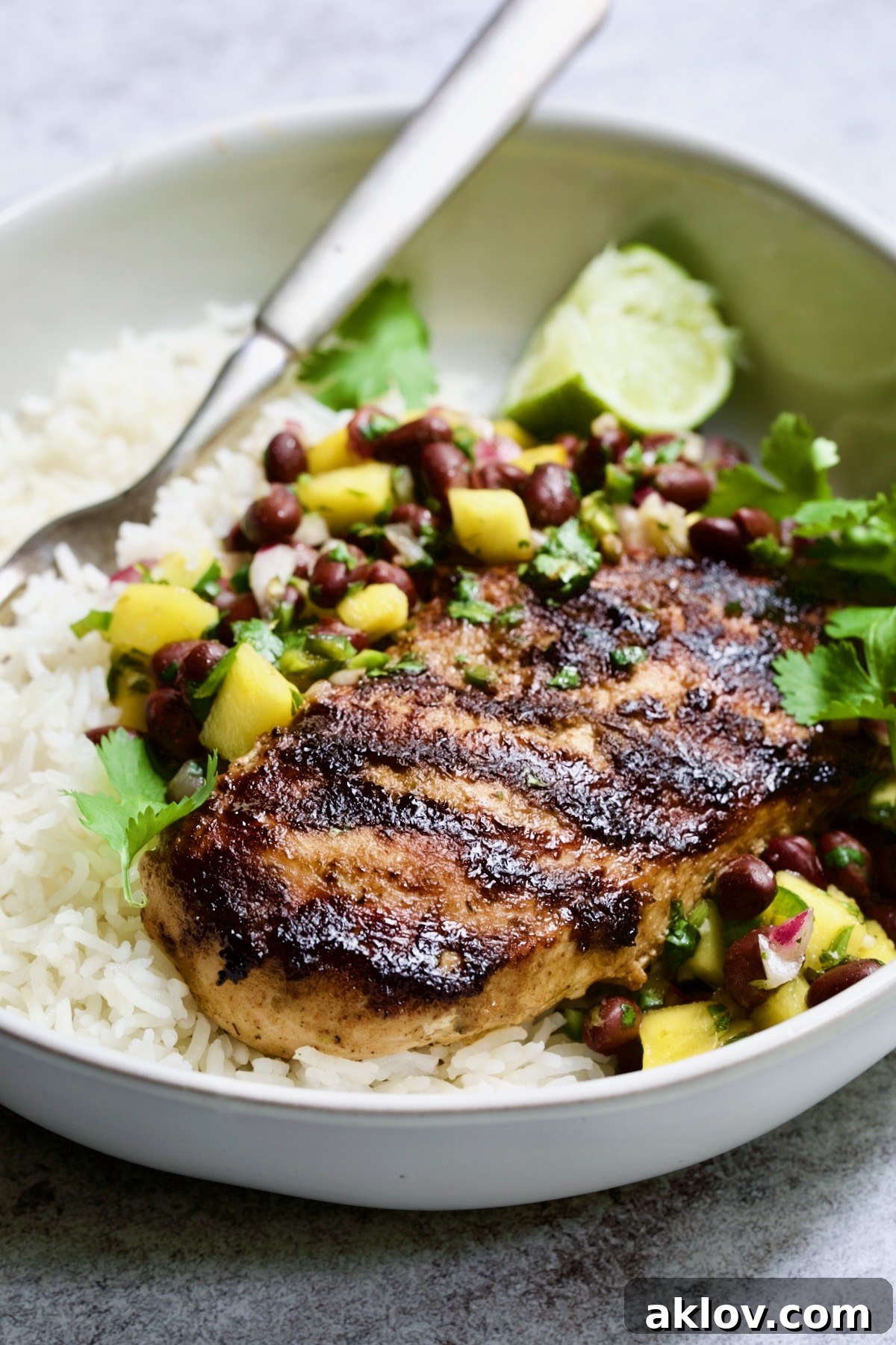 Caribbean Jerk Chicken with Mango Black Bean Salsa with rice in white bowl.