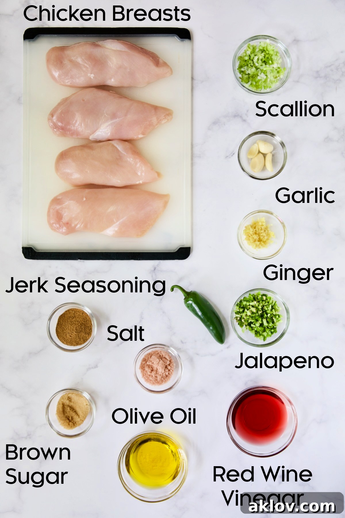 Ingredients for Caribbean Jerk Chicken on glass bowls and four uncooked chicken breasts on white cutting board.