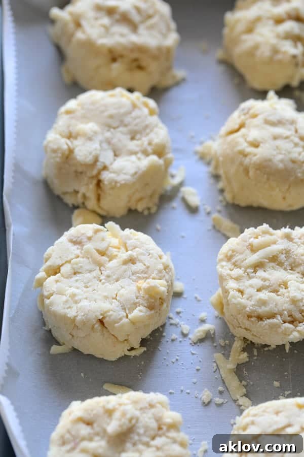 Photo of Pepper Jack Biscuit Topping formed into biscuits on parchment paper before baking. Each biscuit is evenly shaped.