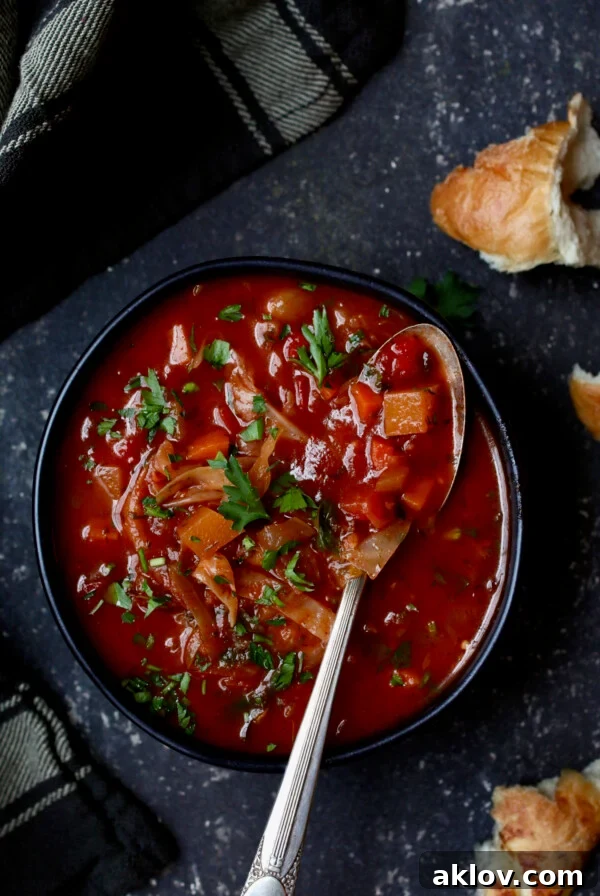 Rustic Cabbage and Root Vegetable Soup in black bowl garnished with parsley.