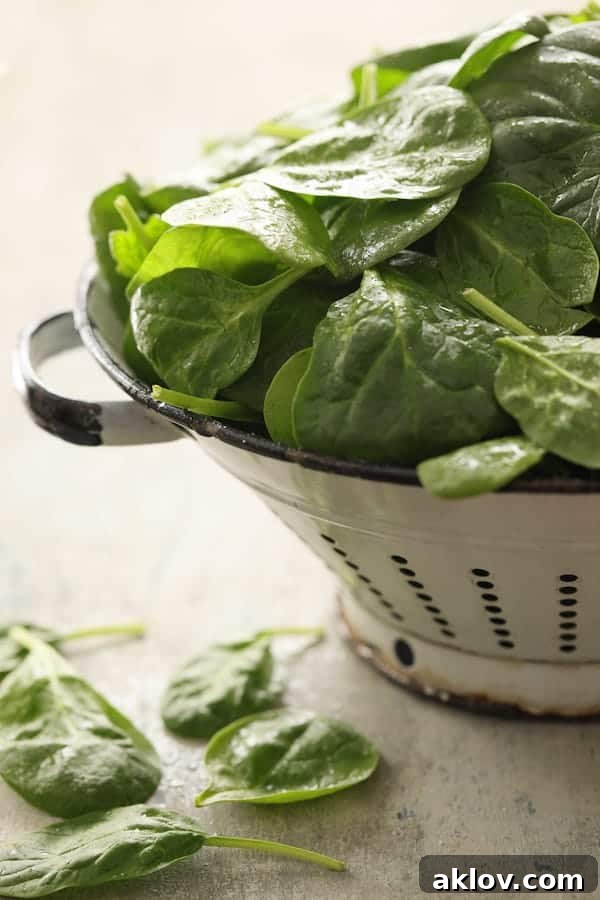 Photo of vibrant fresh spinach in a white colander, ready for use in the recipe.