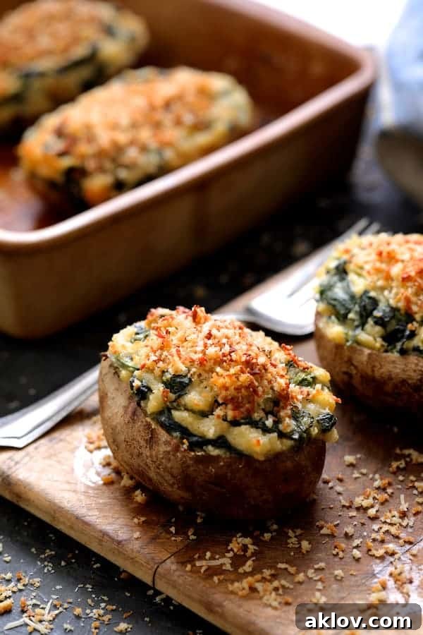 Photo of finished Spinach Parmesan Ranch Twice Baked Potatoes presented on a small wooden cutting board, with a serving fork and the baking dish in the background.