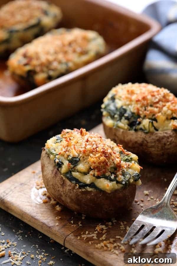 Photo of Spinach Parmesan Ranch Twice Baked Potatoes displayed beautifully on a small wooden cutting board, with a serving fork nearby.