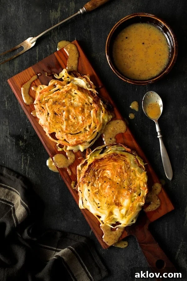 Caramelized Cabbage Steaks with Tangy Dijon Dressing 5 Photo of Roasted Cabbage Steaks with Mustard Vinaigrette on wood cutting board with gray striped towel.