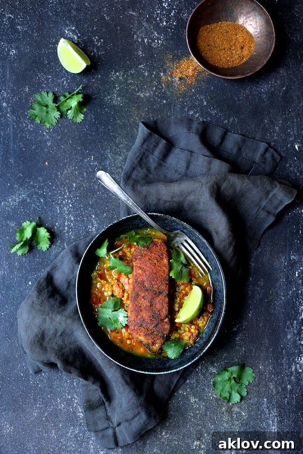 Masala-Crusted Sea Bass with Hearty Red Lentil Daal 2 Indian Spiced Sea Bass with Braised Red Lentils presented beautifully on a blue plate with a deep blue napkin and fresh cilantro garnishes.