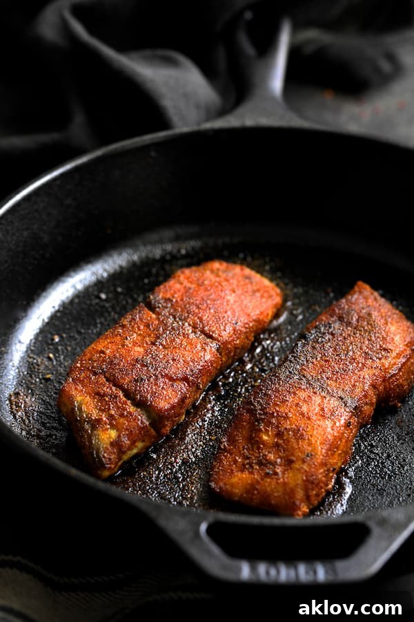 Masala-Crusted Sea Bass with Hearty Red Lentil Daal 5 A plump sea bass fillet, beautifully seared to a golden-brown perfection, rests in a cast iron skillet, ready to be finished in the oven.