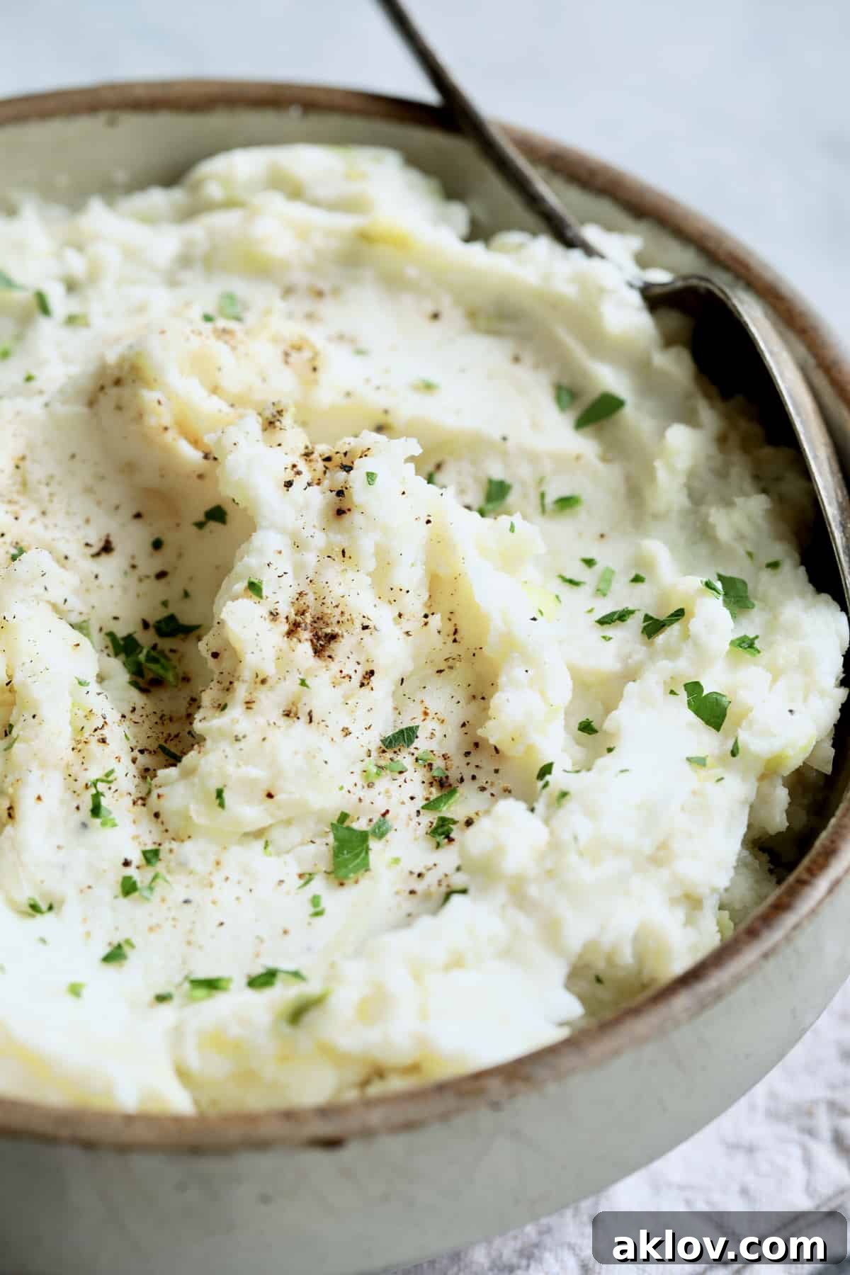 A close-up shot of a stoneware bowl filled with perfectly mashed Colcannon, garnished with fresh parsley, highlighting its creamy texture and comforting appeal.