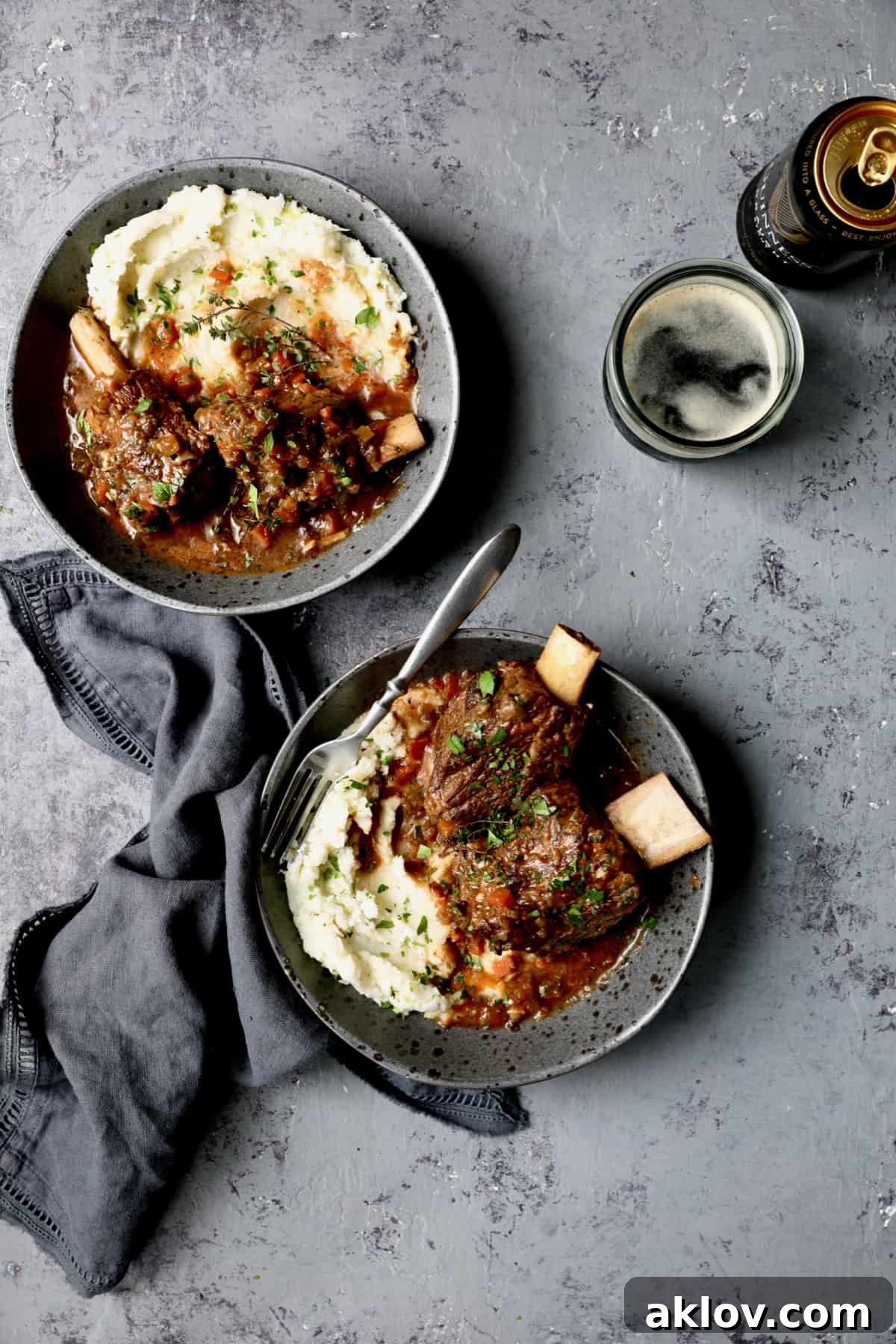 A beautifully composed photo featuring Stout Braised Beef Short Ribs and Colcannon, elegantly presented on a gray background, accompanied by a glass of stout beer, creating an inviting and hearty culinary scene.