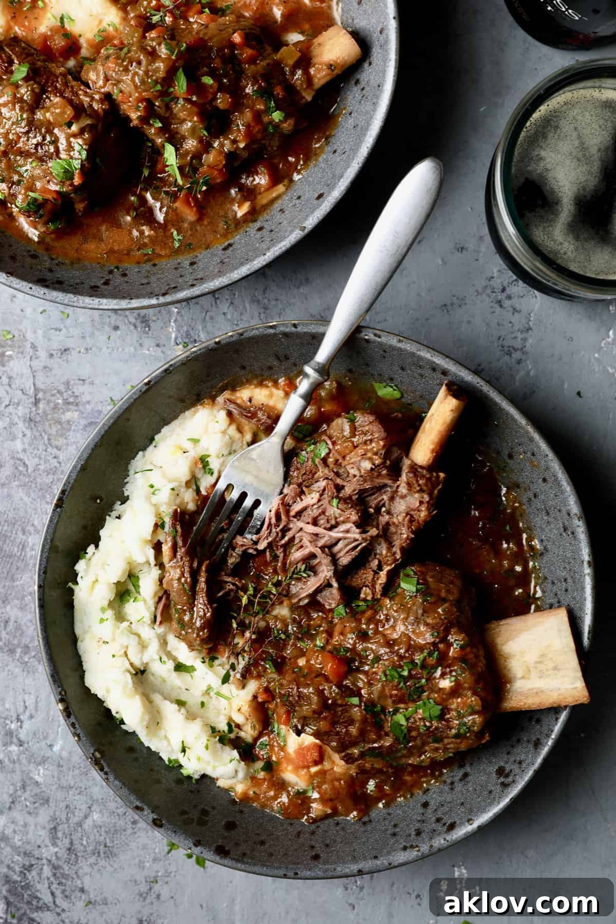 A close-up action shot capturing the tender perfection of Stout Braised Beef Short Ribs and Colcannon, with a fork gently shredding one of the short ribs to highlight its incredible tenderness.