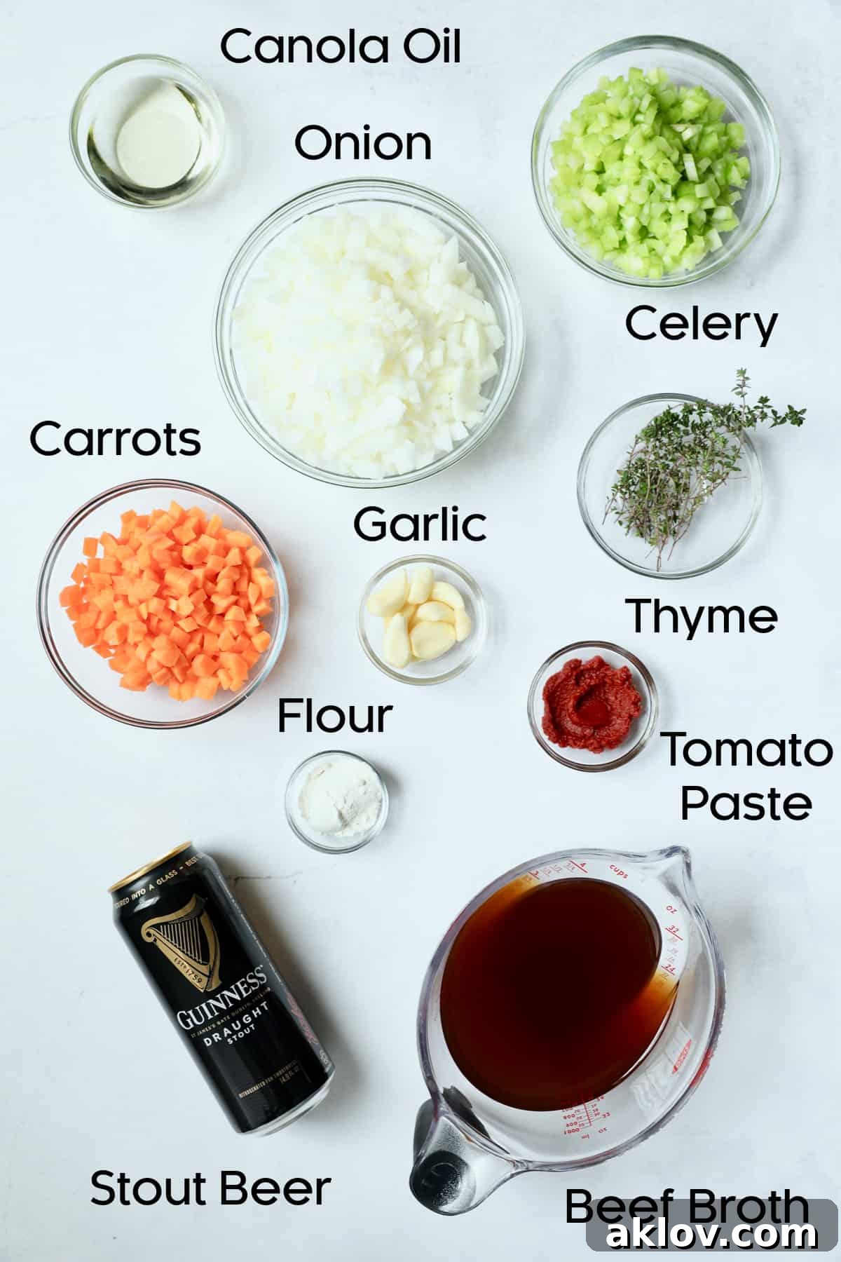 A vibrant collection of fresh ingredients for Stout Braised Beef Short Ribs, including aromatic vegetables like chopped onions, carrots, and celery, alongside robust garlic and sprigs of fresh thyme, laid out on a clean surface.