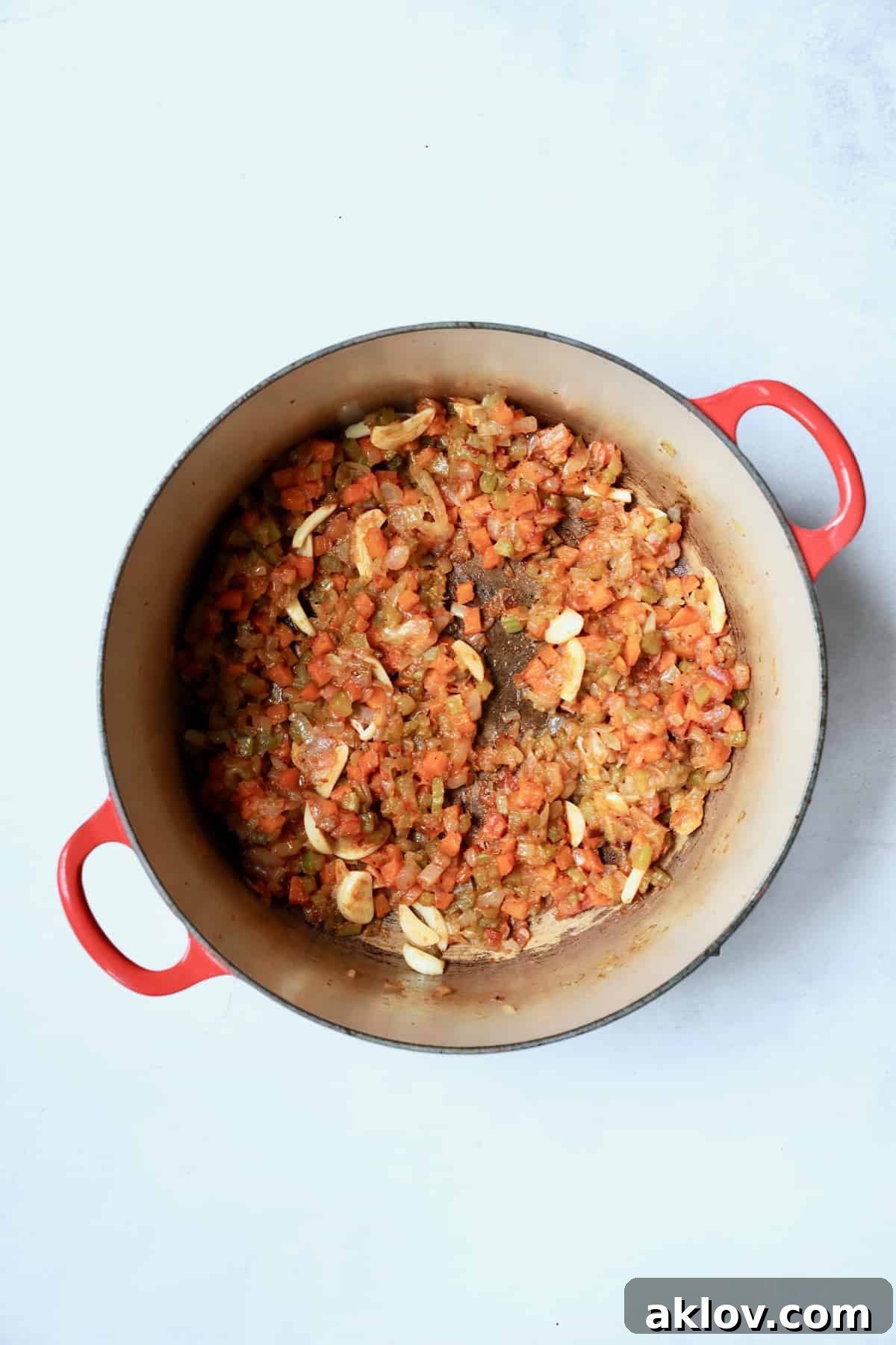 Cooked onions, celery, and carrots coated with flour and mixed with rich tomato paste, creating a savory base in the Dutch oven, ready for the liquid ingredients.