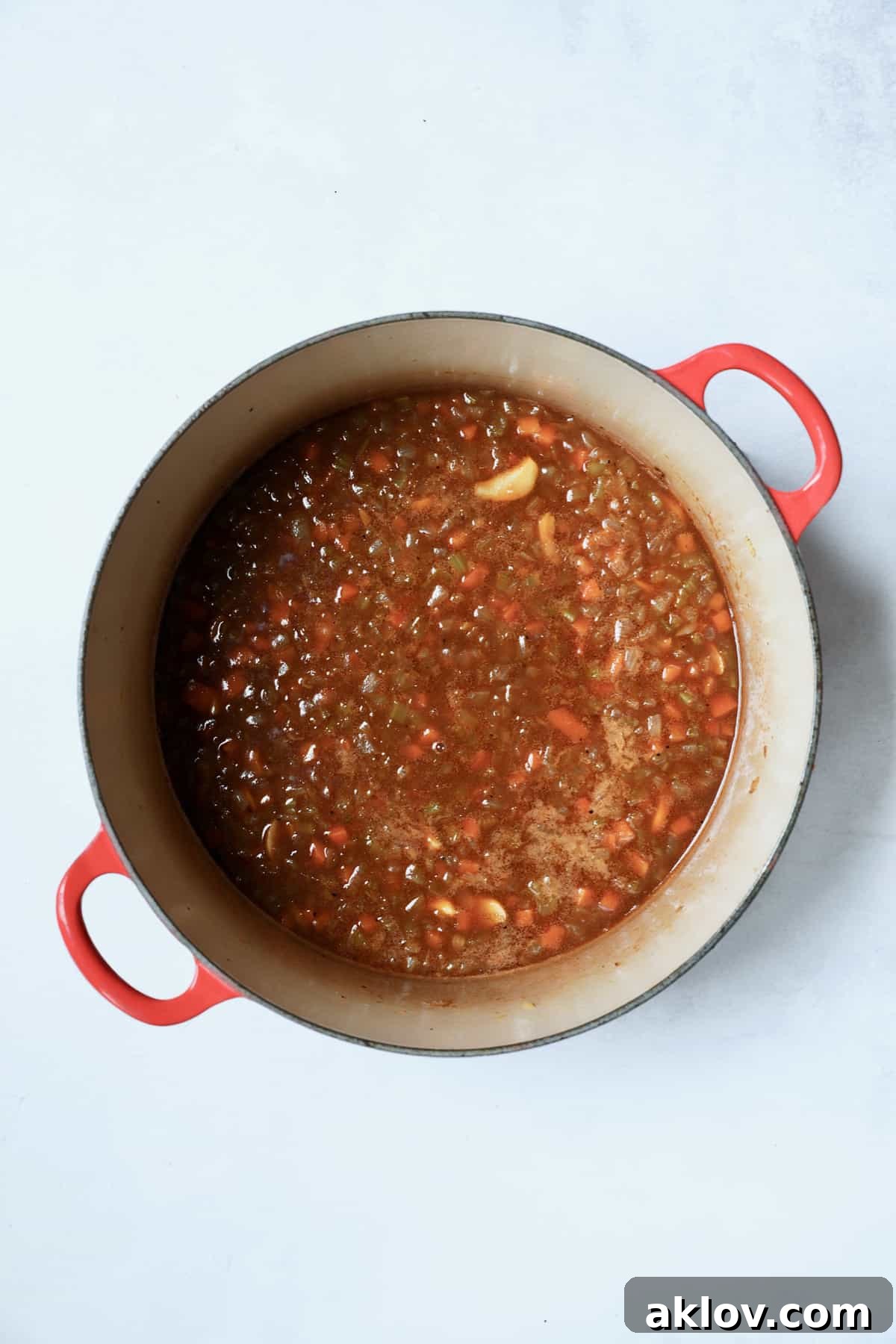 A process photo showing the Stout Braised Beef Short Ribs preparation with a dark stout beer being poured into the Dutch oven, creating a rich, bubbling liquid that will form the braising sauce.