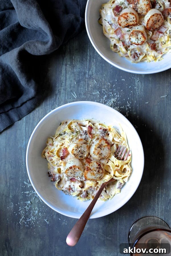 Elegantly plated Seared Sea Scallops with Spicy Bacon and Sun Dried Tomato Alfredo Sauce, served in a white bowl on a gray background with a complementary gray napkin, ready for a gourmet dining experience.