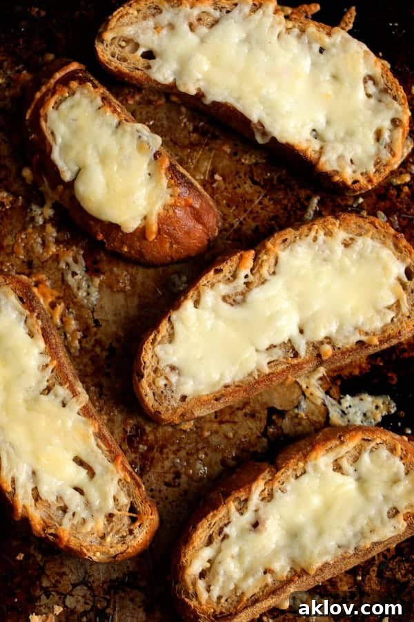 A baking sheet featuring five pieces of golden-brown Manchego Toast, with melted, bubbly cheese on rustic bread.