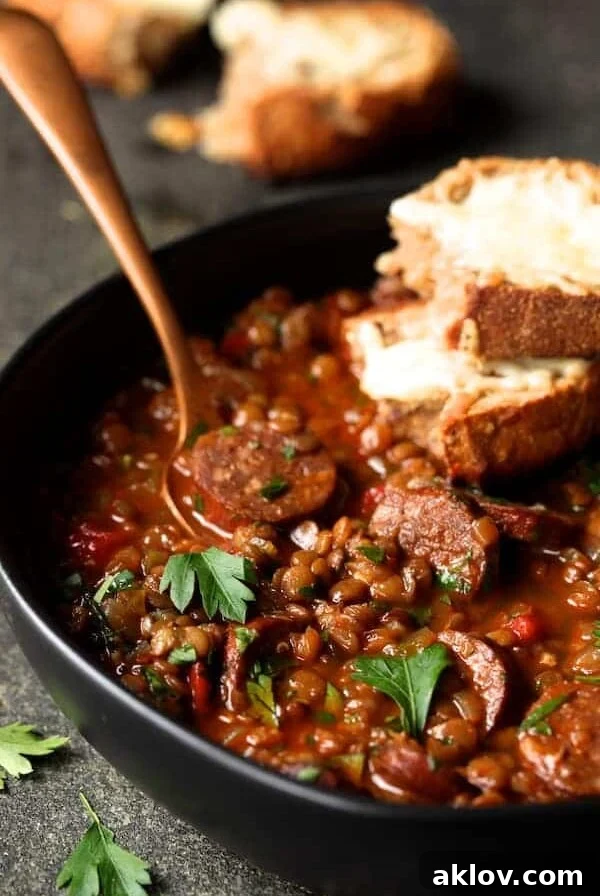 Soupy Spanish Lentils with Chorizo and Manchego Toast in black bowl with copper fork.