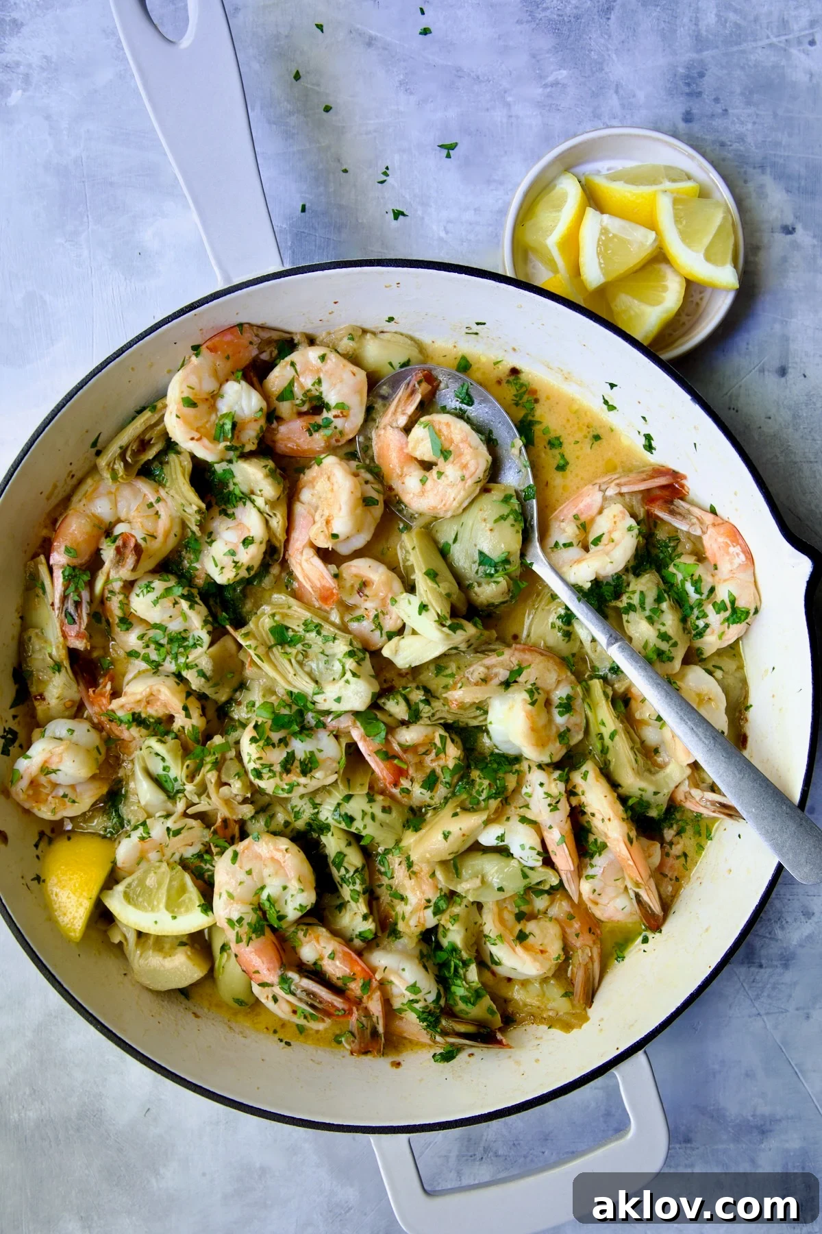 Golden Shrimp Scampi with Artichokes glistening in a white enamel cast iron pan, ready to be served.