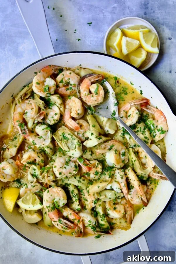 Shrimp Scampi with Artichokes in white enamel cast iron pan with serving spoon.