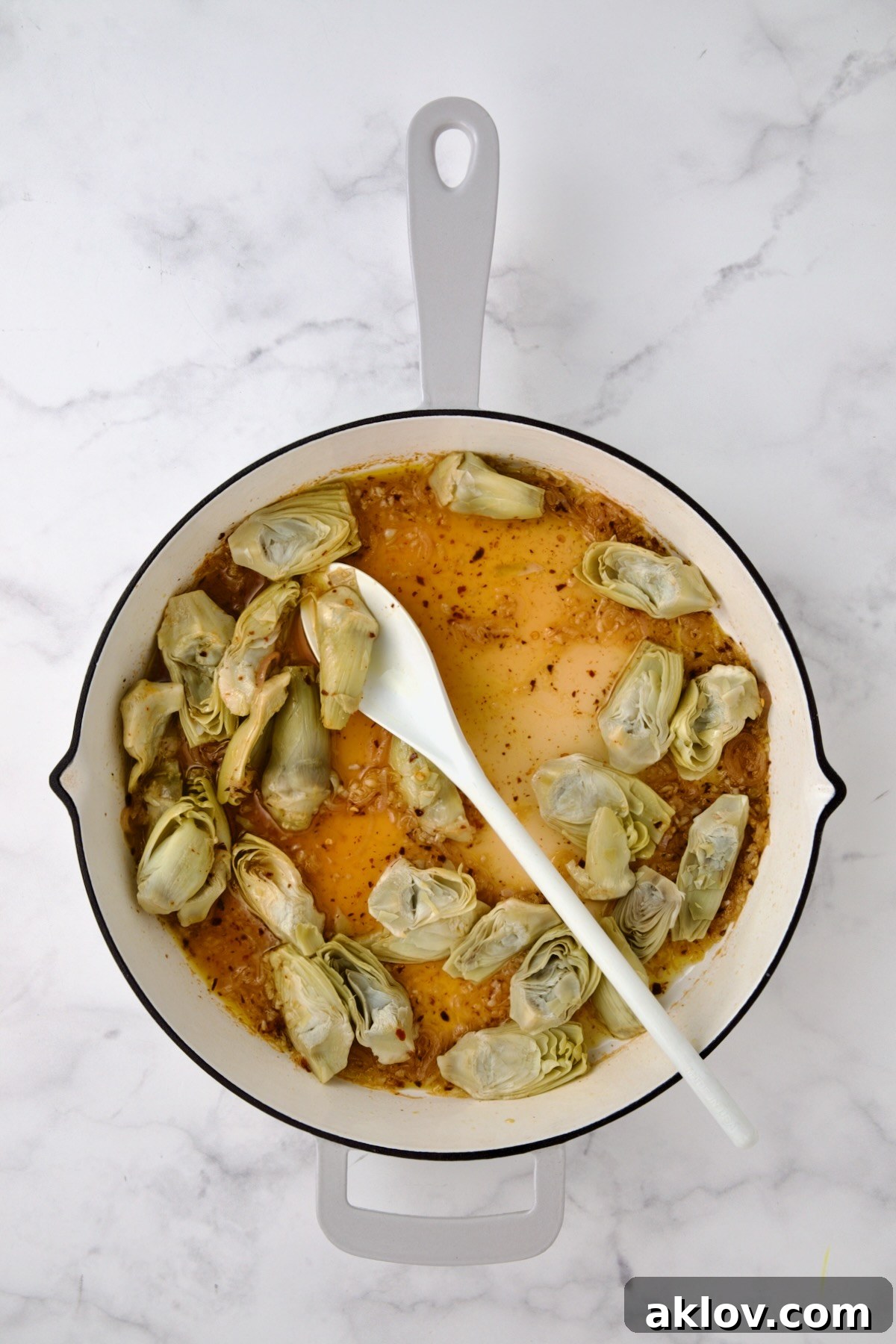 Tender artichoke hearts mingling with the wine and shallot mixture in the pan.