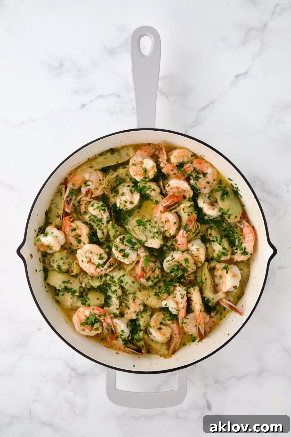 The vibrant final presentation of Shrimp Scampi with Artichokes, garnished with fresh parsley and lemon.