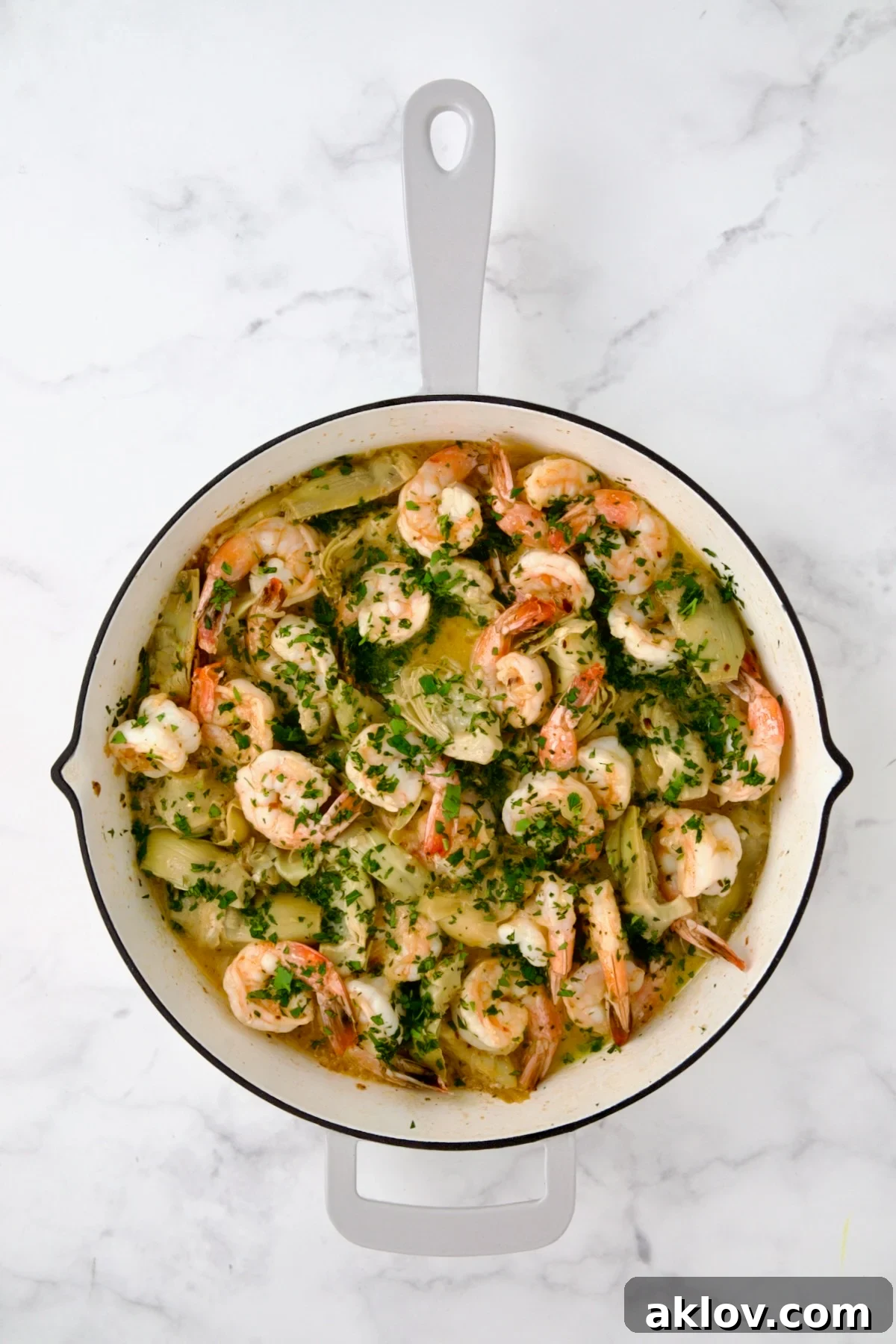 Finished Shrimp Scampi with Artichokes in white enamel cast iron pan.