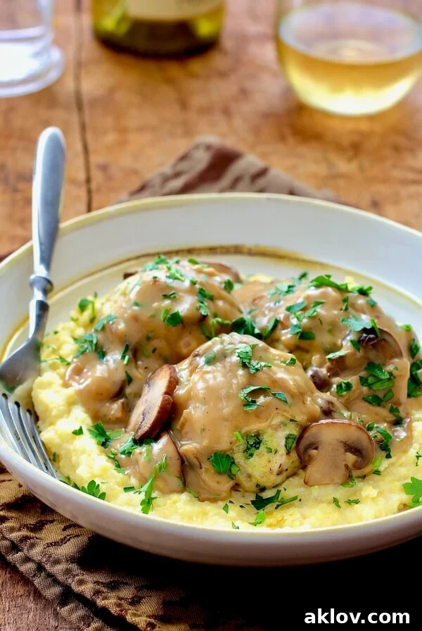 Chicken Marsala Meatballs with Parmesan Polenta in white bowl with fork.