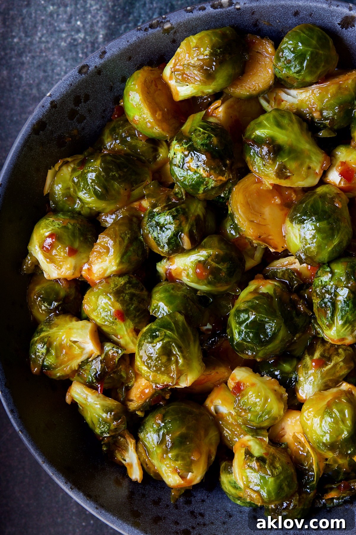 Glazed Sriracha Sweet Chili Brussels Sprouts 14 Another vibrant image of Sriracha Sweet Chili Roasted Brussels Sprouts served in a gray speckled bowl, ready to be enjoyed.