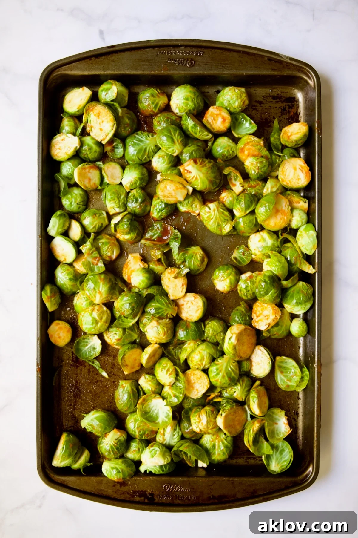 Glazed Sriracha Sweet Chili Brussels Sprouts 8 Halved Brussels sprouts on a baking sheet, now fully coated with Sriracha, ready for their cut sides to be placed down.