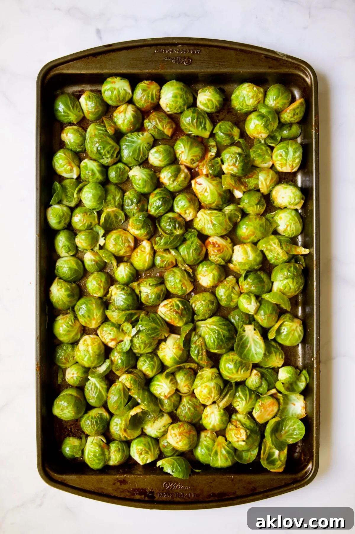 Glazed Sriracha Sweet Chili Brussels Sprouts 9 Halved Brussels sprouts on a baking sheet, all arranged with their cut sides facing down, prepared for roasting.