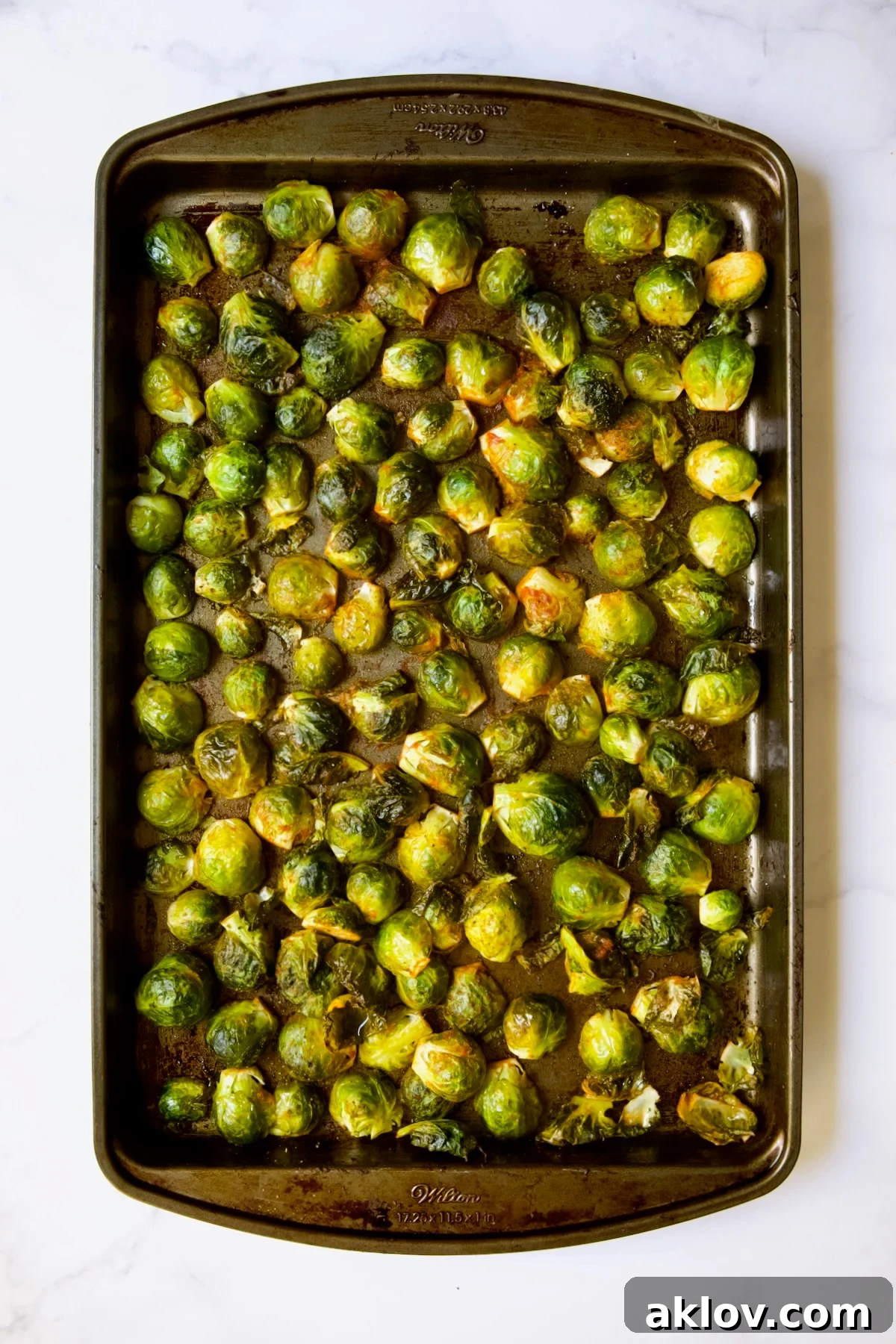 Glazed Sriracha Sweet Chili Brussels Sprouts 10 Roasted Brussels sprouts on a baking sheet, showing their caramelized and lightly browned cut sides after cooking.