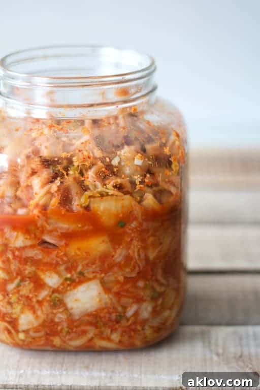 Photo of jar of homemade kimchi on a rustic wood surface, highlighting the key ingredient for the soup.