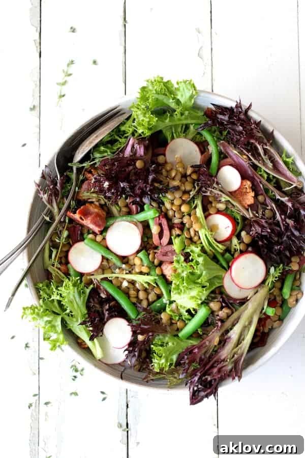 Rustic French Lentil Salad 9 Photo of French Lentil Salad on white background in white bowl with serving spoon and fork.
