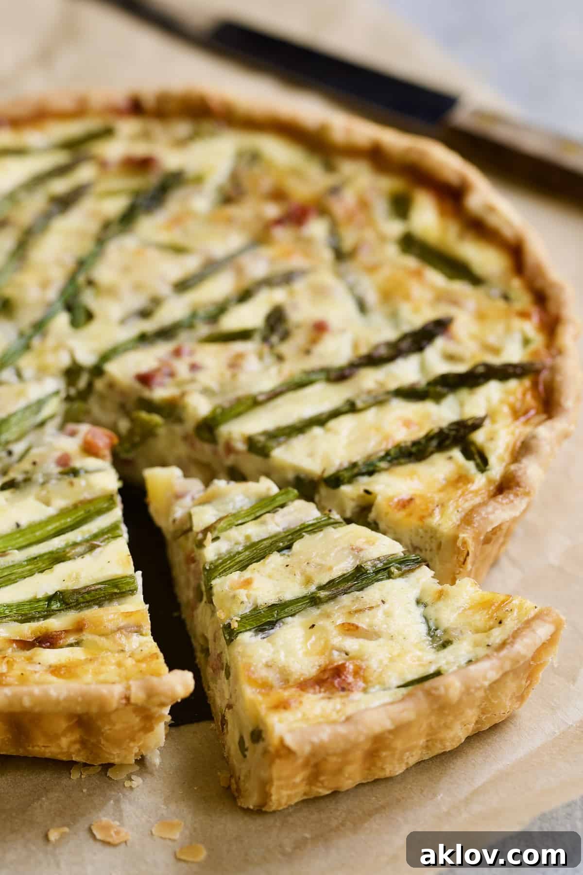 Savory Asparagus Tart with Prosciutto and Fontina 3 Photo of a single slice of Asparagus Prosciutto and Fontina Tart on a white plate, revealing its layers of ingredients.