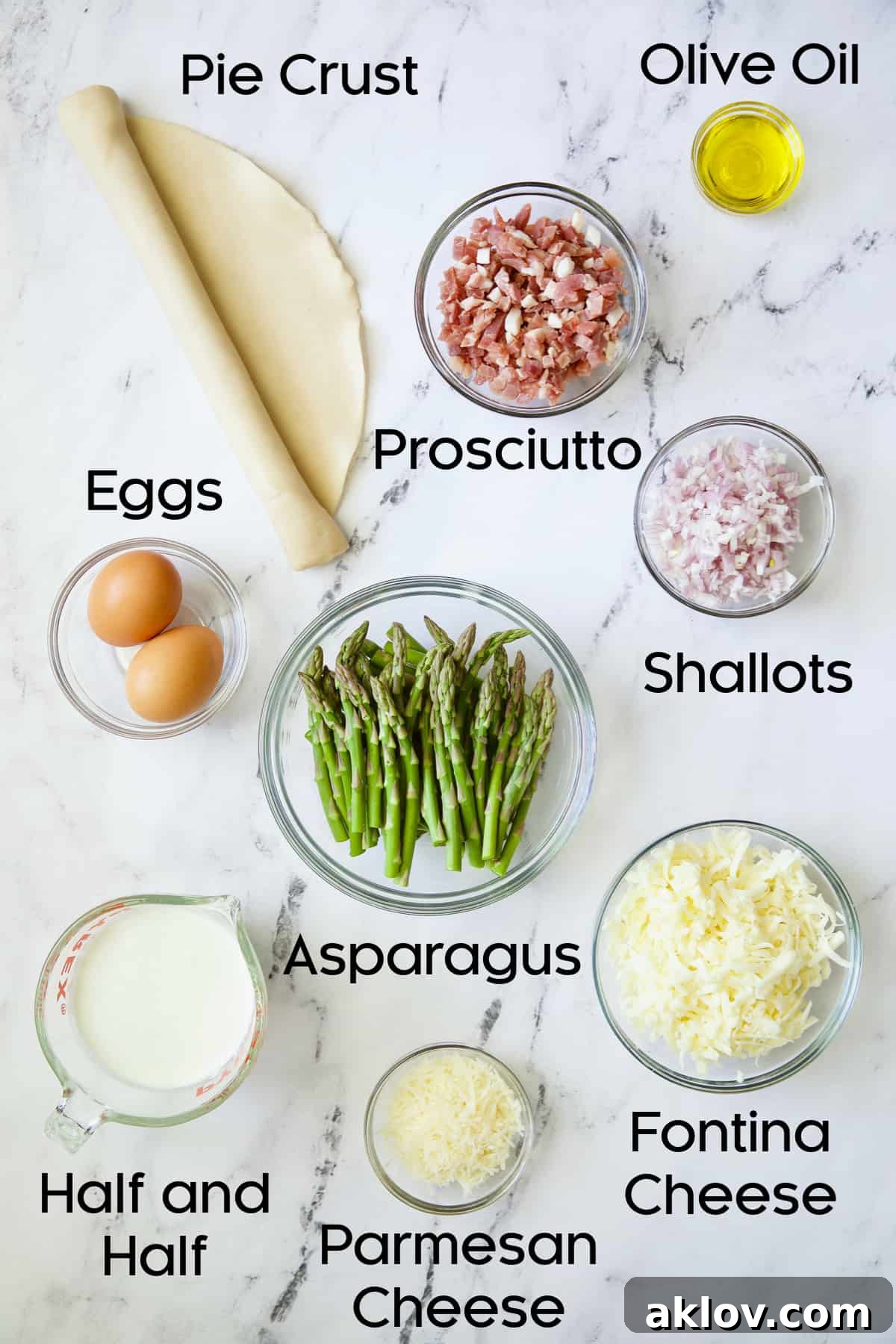 Savory Asparagus Tart with Prosciutto and Fontina 4 Photo of various fresh ingredients laid out on a kitchen counter for making Asparagus Prosciutto and Fontina Tart, including asparagus, prosciutto, cheese, and eggs.