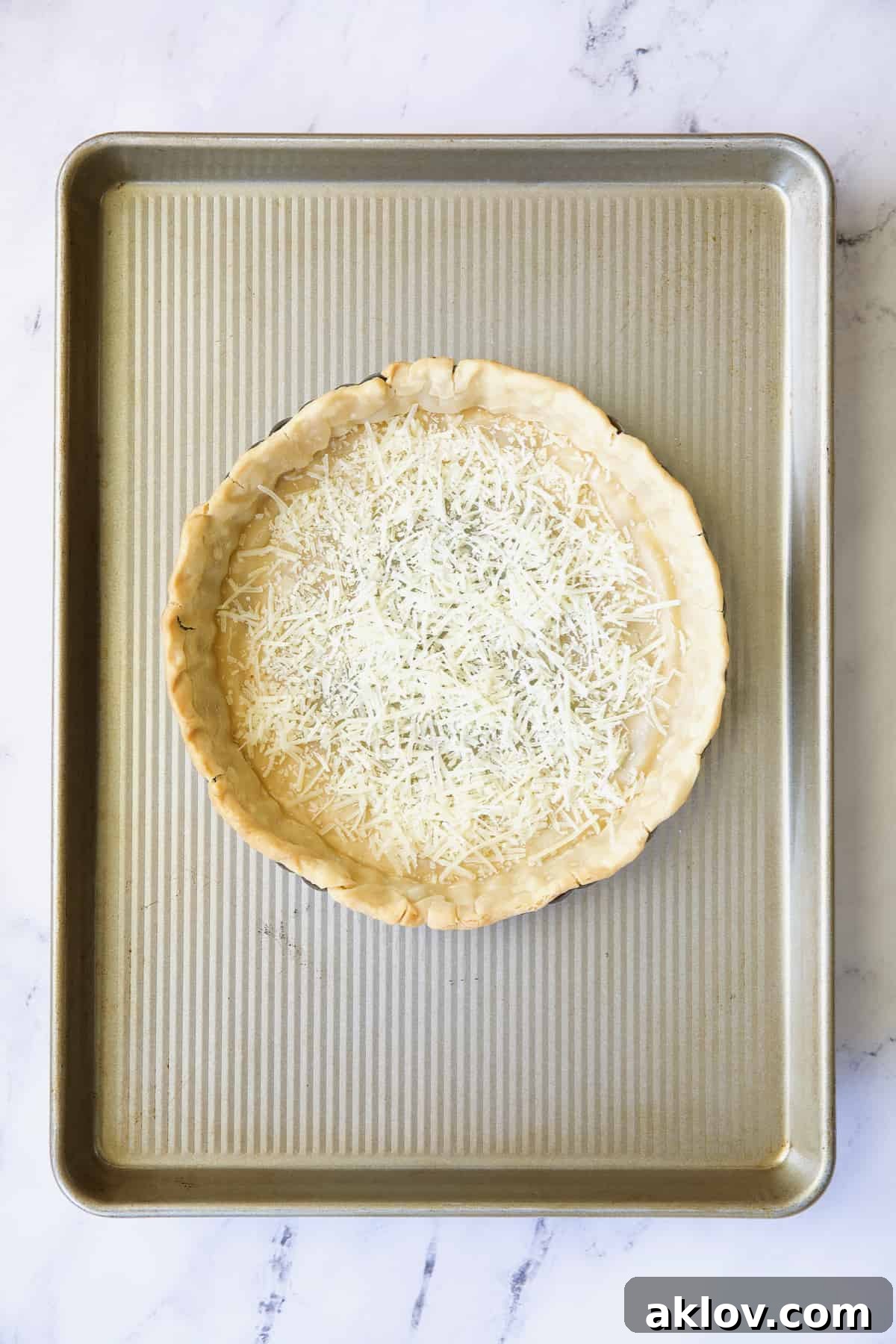 Savory Asparagus Tart with Prosciutto and Fontina 6 Photo of a blind-baked pie crust in a tart pan, placed on a baking sheet, with a layer of Parmesan cheese sprinkled on the bottom.