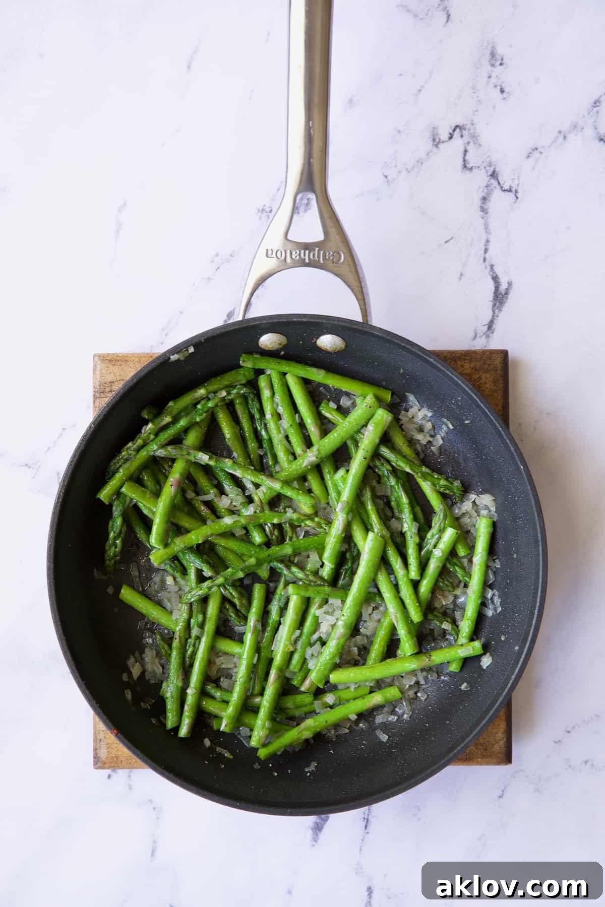 Savory Asparagus Tart with Prosciutto and Fontina 8 Photo of bright green, sautéed asparagus and shallots in a nonstick skillet, glistening with olive oil.