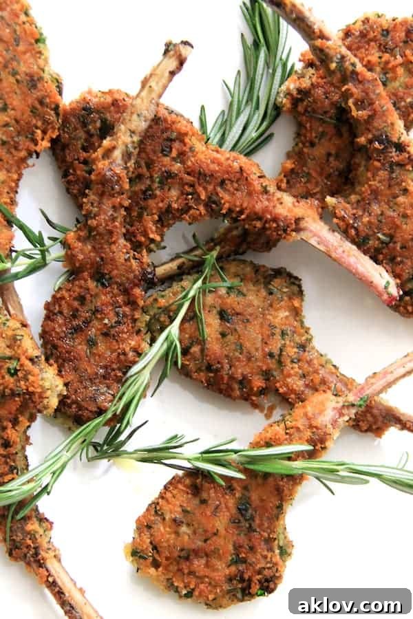 Photo of Parmesan and Herb-Crusted Lamb Chops on white background with rosemary sprigs.