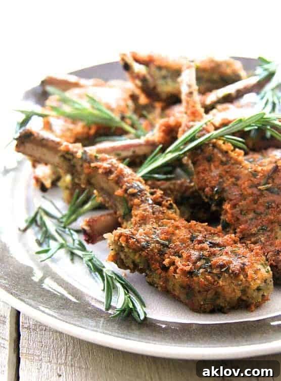 Close-up photo of Parmesan and Herb-Crusted Lamb Chops on gray-rimmed platter garnished with rosemary.