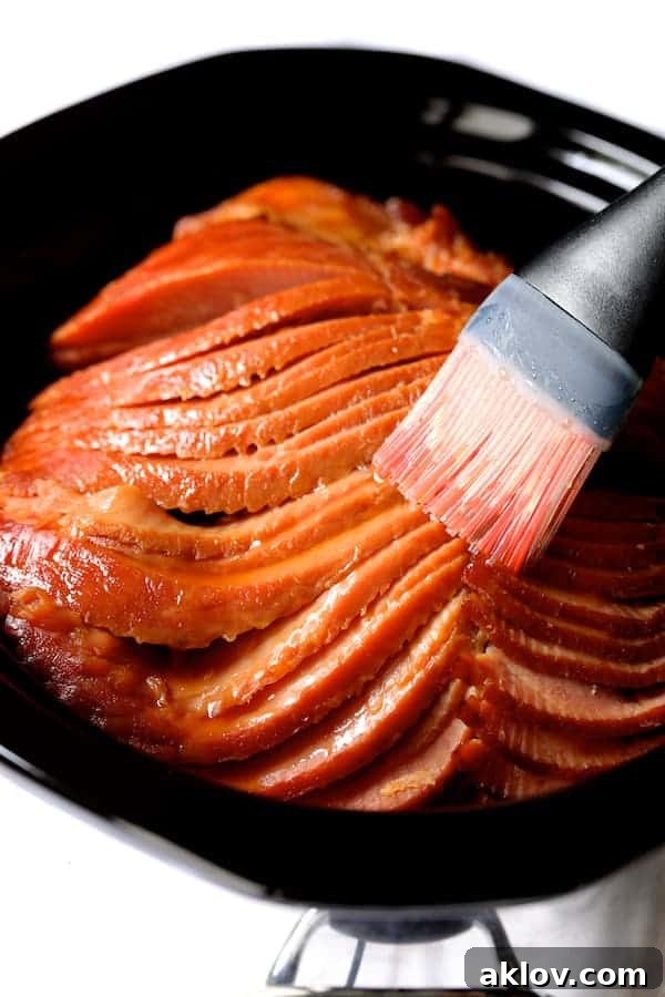 Photo of spiral ham being brushed with pastry brush in slow cooker.