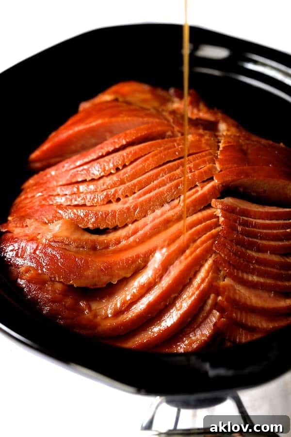 Photo of glaze being drizzled over spiral sliced ham in slow cooker.