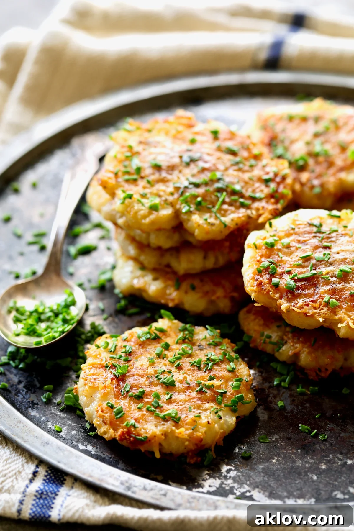 Crispy Parmesan Crusted Crushed Turnips served on a sleek stainless steel tray, beautifully garnished with fresh green chives.