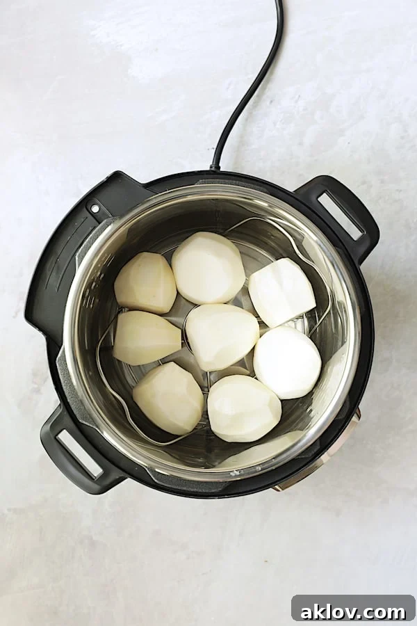 An overhead shot of raw, peeled turnips carefully arranged on the steaming rack inside an Instant Pot, ready for pressure cooking.