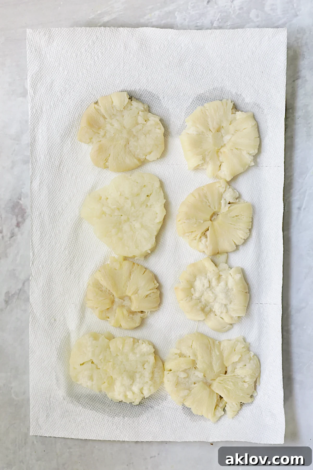 Eight perfectly smashed turnips arranged on paper towels, allowing excess moisture to drain before the next cooking stage.